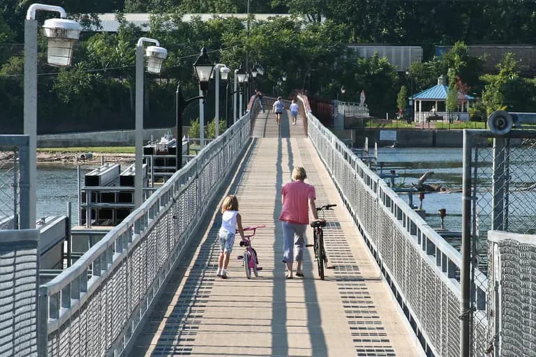 A family walking bicycles across the Sinnissippi Dam walkway